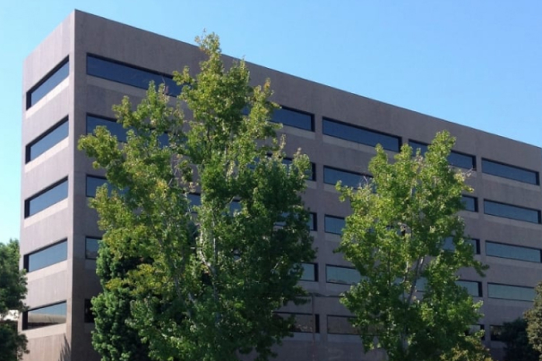Modern multi-story residential or institutional building with horizontal striping and green trees in front.